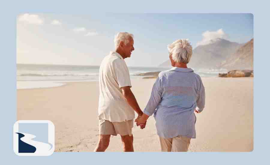 Elder couple walking on the beach and holding hands
