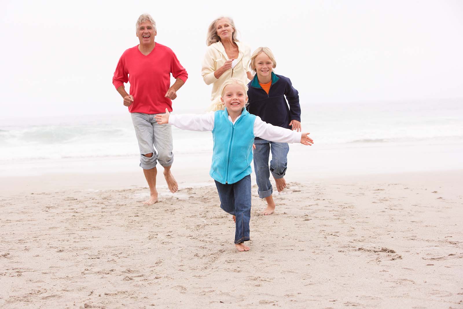 Grandparents And Grandchildren Running On Winter Beach Together